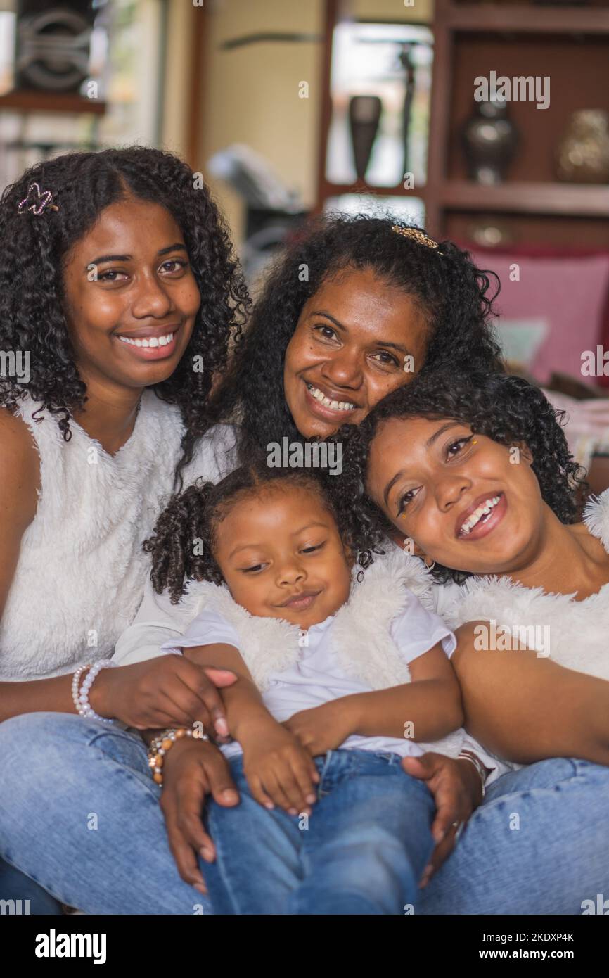 Cheerful Indian Mother And Daughters With Curly Hair In Casual Wear Sitting Together On Sofa In 7639