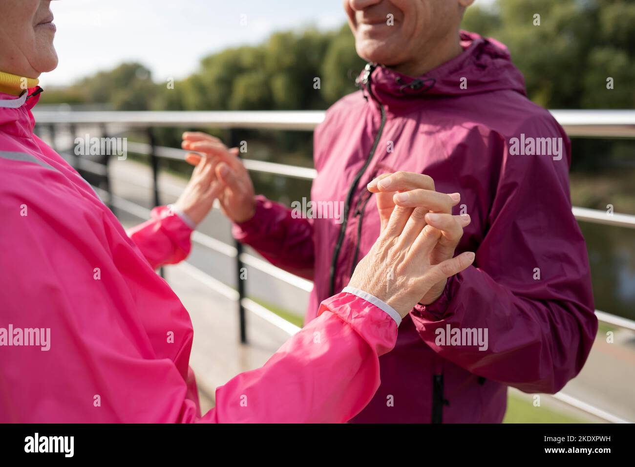 Crop mature sportsman and sportswoman in activewear smiling and