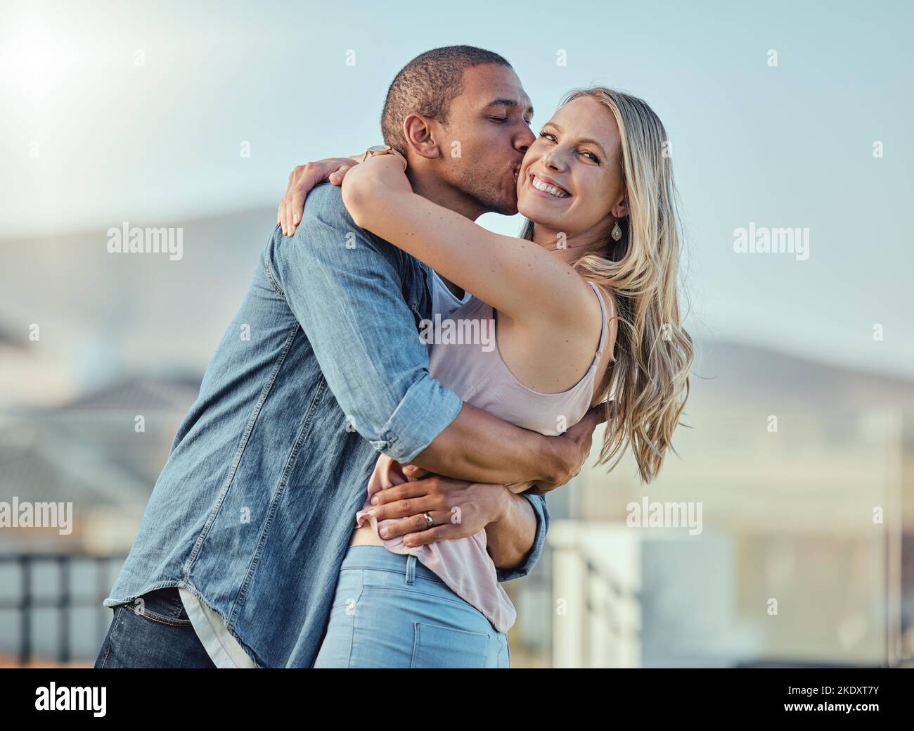 Interracial man and woman, love and kiss outside feeling happy, in love and caring in the city. Romance, romantic and boyfriend and girlfriend Stock Photo