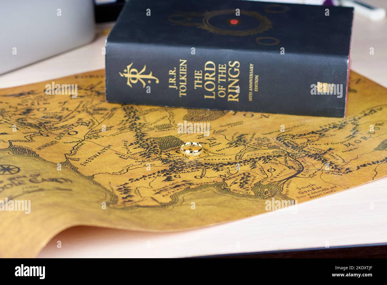 Astrakhan, Russia - 11.09.2022: Golden Ring of Power lies on the map of Middle-Earth besides The Lord of the Rings book Stock Photo