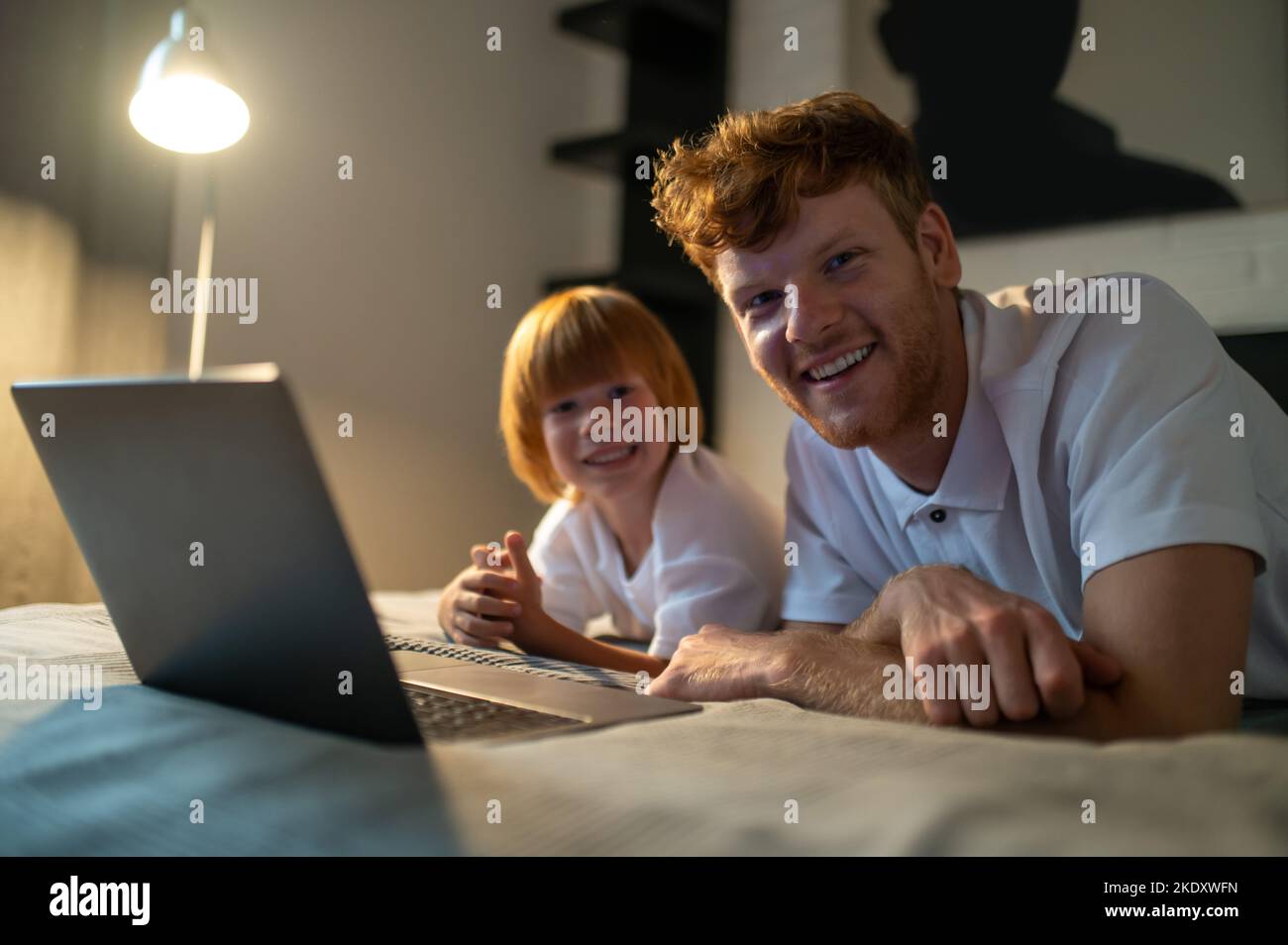 Dad and son spending time together in bed before going to sleep Stock Photo