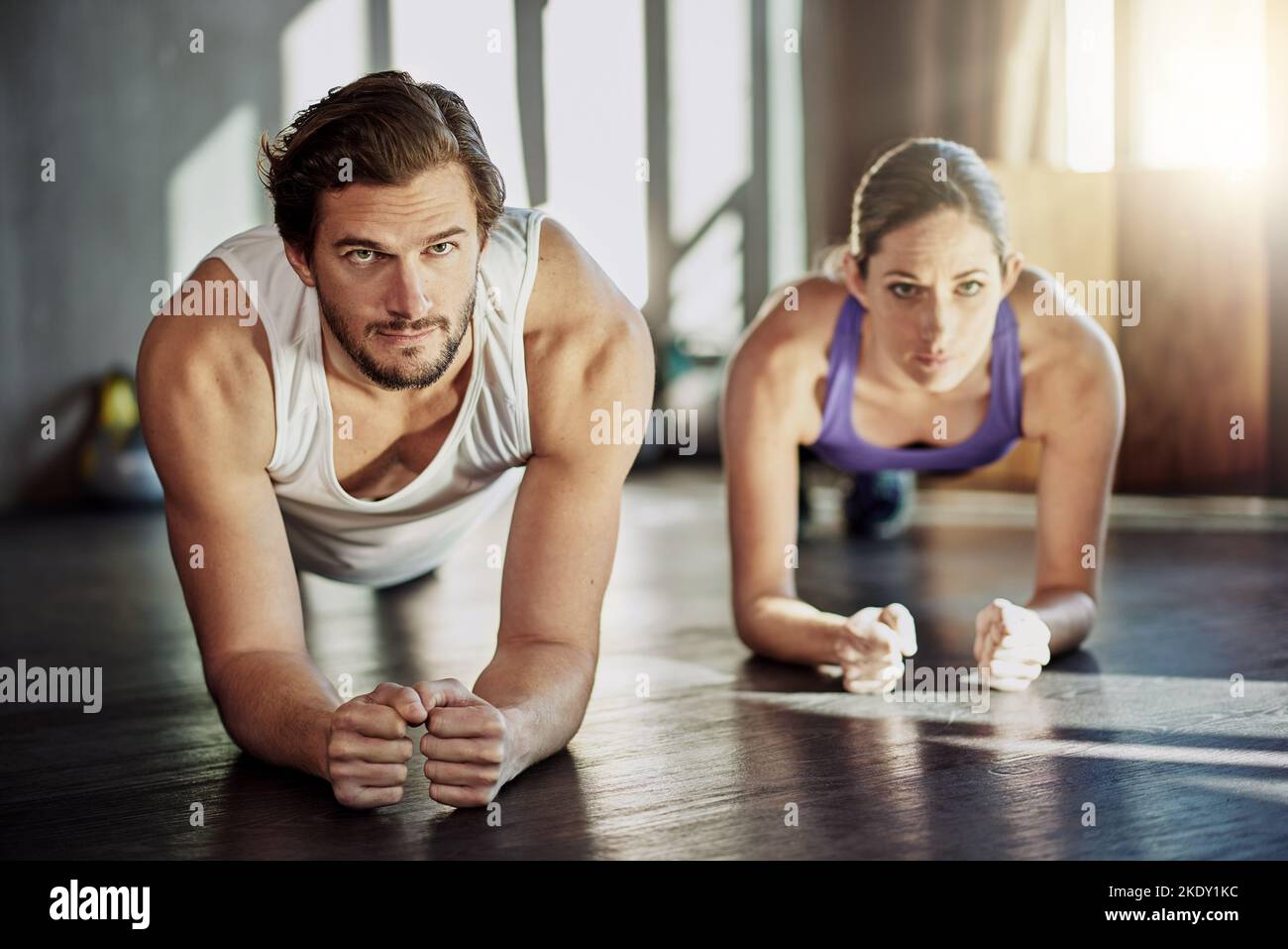 Seeing who can hold it the longest. two young people planking together as part of their workout. Stock Photo