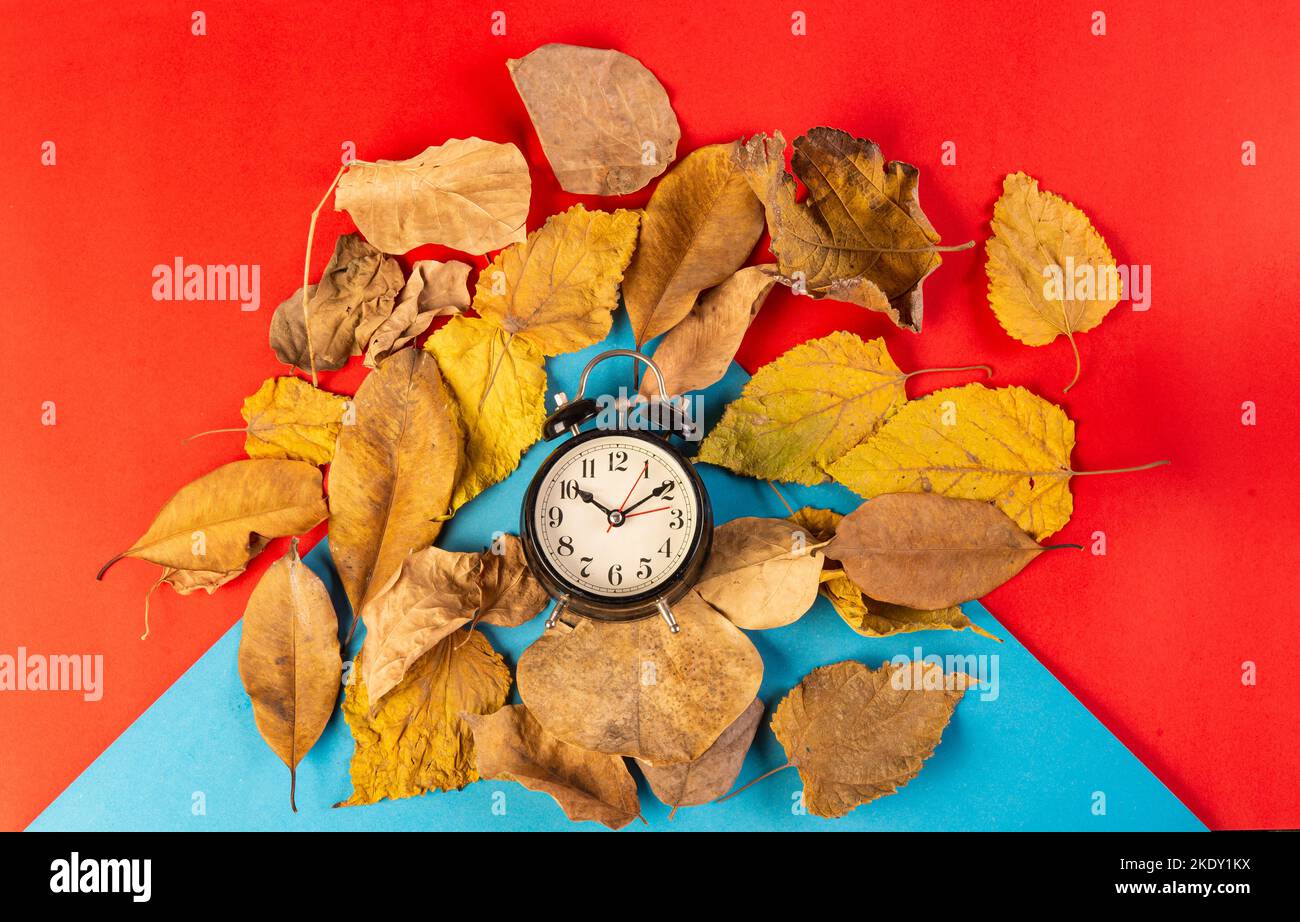 Its autumn time theme with yellow leaves and clock on red banner ...