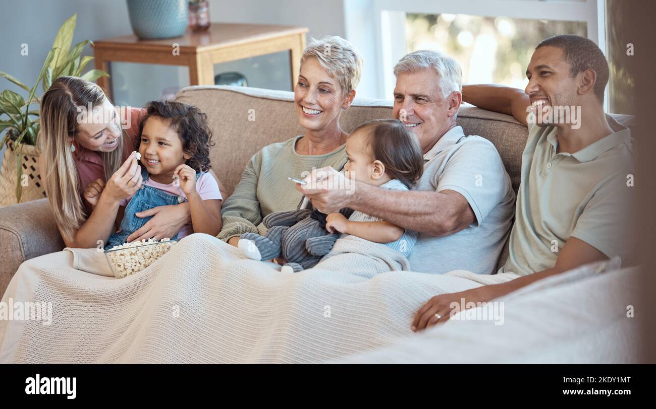 Family, children and watching tv grandparents, parents and kids together on a sofa in the living room of their home. Movie, television and film with a Stock Photo