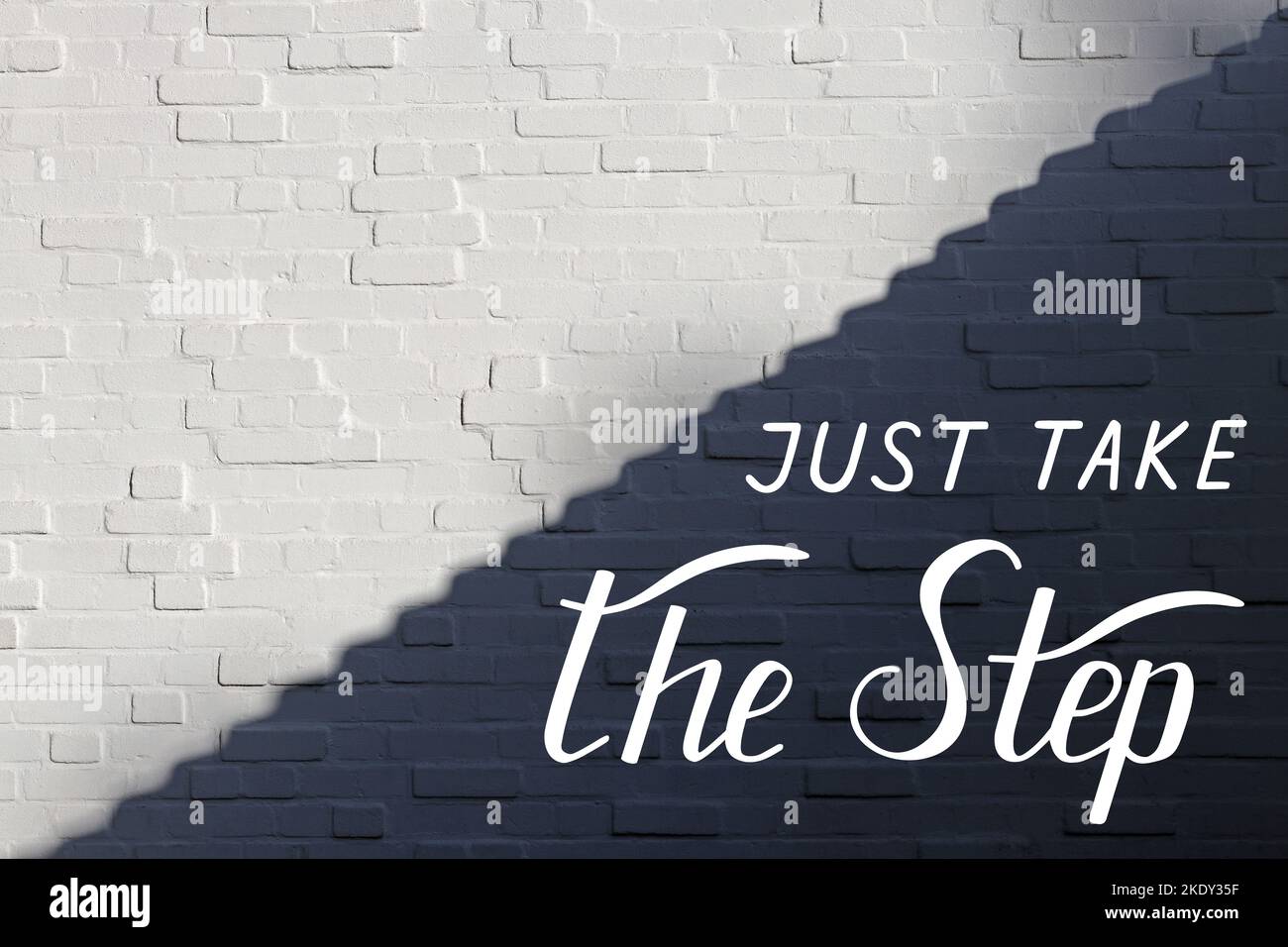 Just take the step - individual handwritten lettering on white brick wall, divided into light and shadow parts along the diagonal in form of steps. Stock Photo