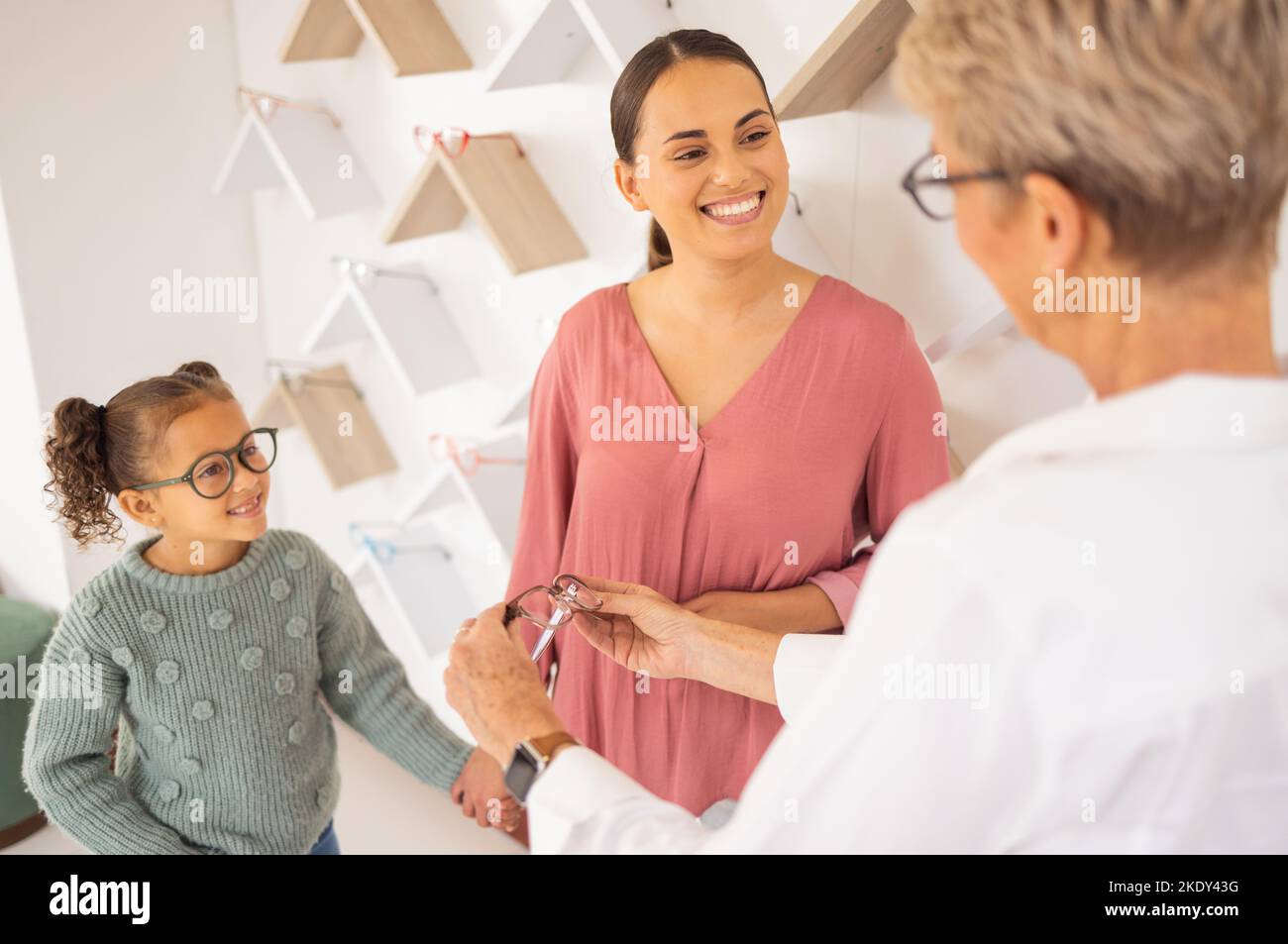 Happy mother, child and and optometrist with glasses eye exam for eyesight, eyes wellness and healthy vision. Girl with mother, eyecare store and Stock Photo