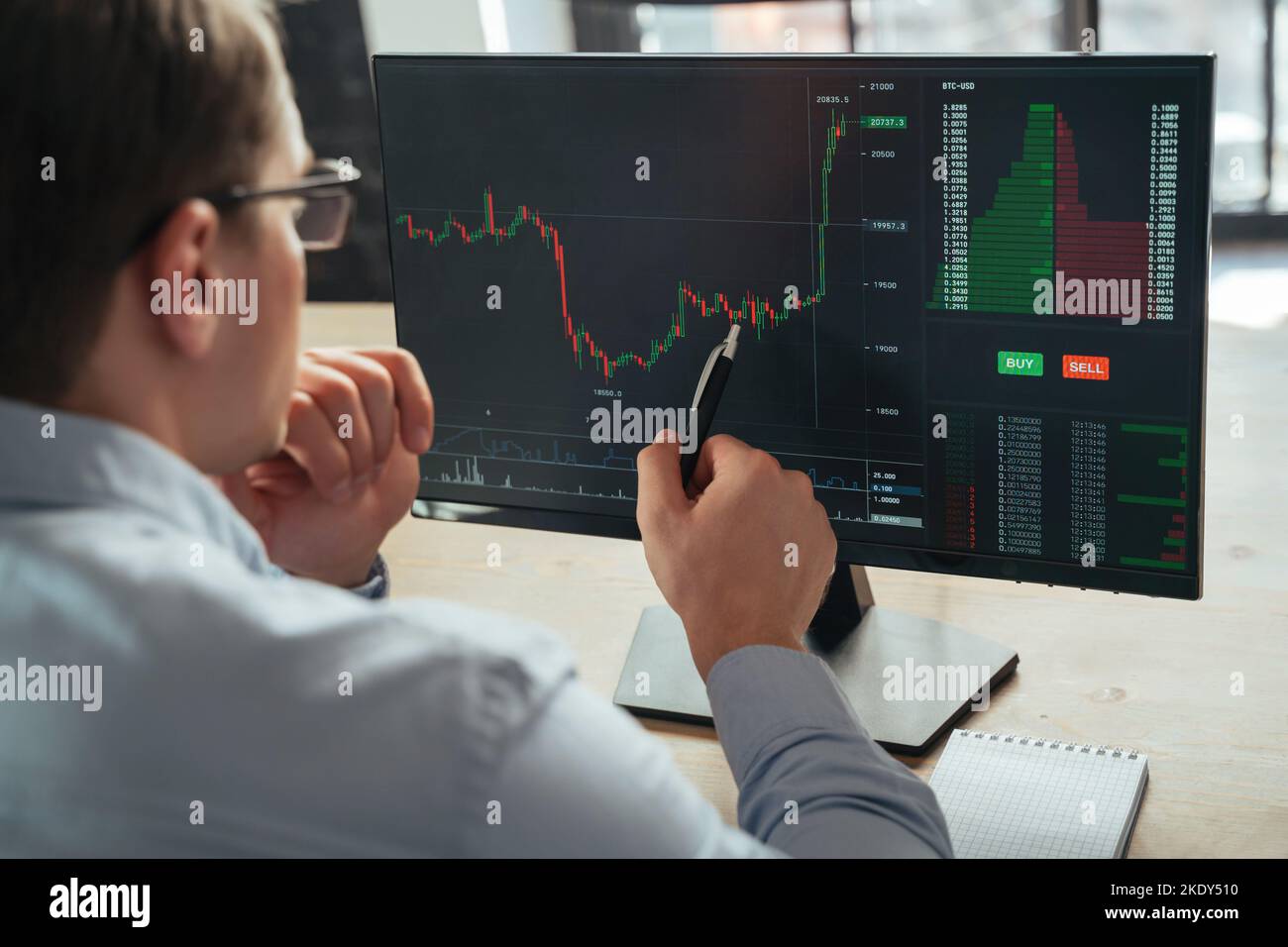 Close up of financial analyst and trader examining attentively investment graph trying to predict future actions of money flow with cryptocurrency app, pointing at screen with pen Stock Photo