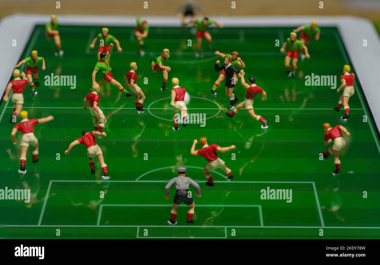 Side view of miniature toys figurines football (soccer) players on a computer electronic pad (focus on the referee). Stock Photo