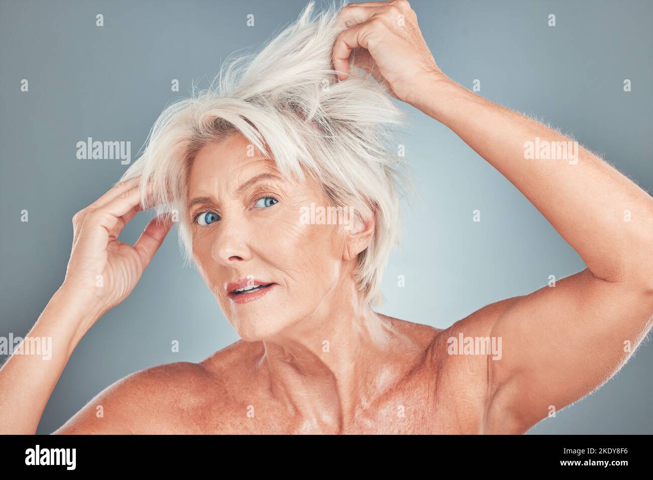 Senior woman, messy hair and stress for salon care, cosmetics or cut against a grey studio background. Portrait of elderly female having a bad hair Stock Photo