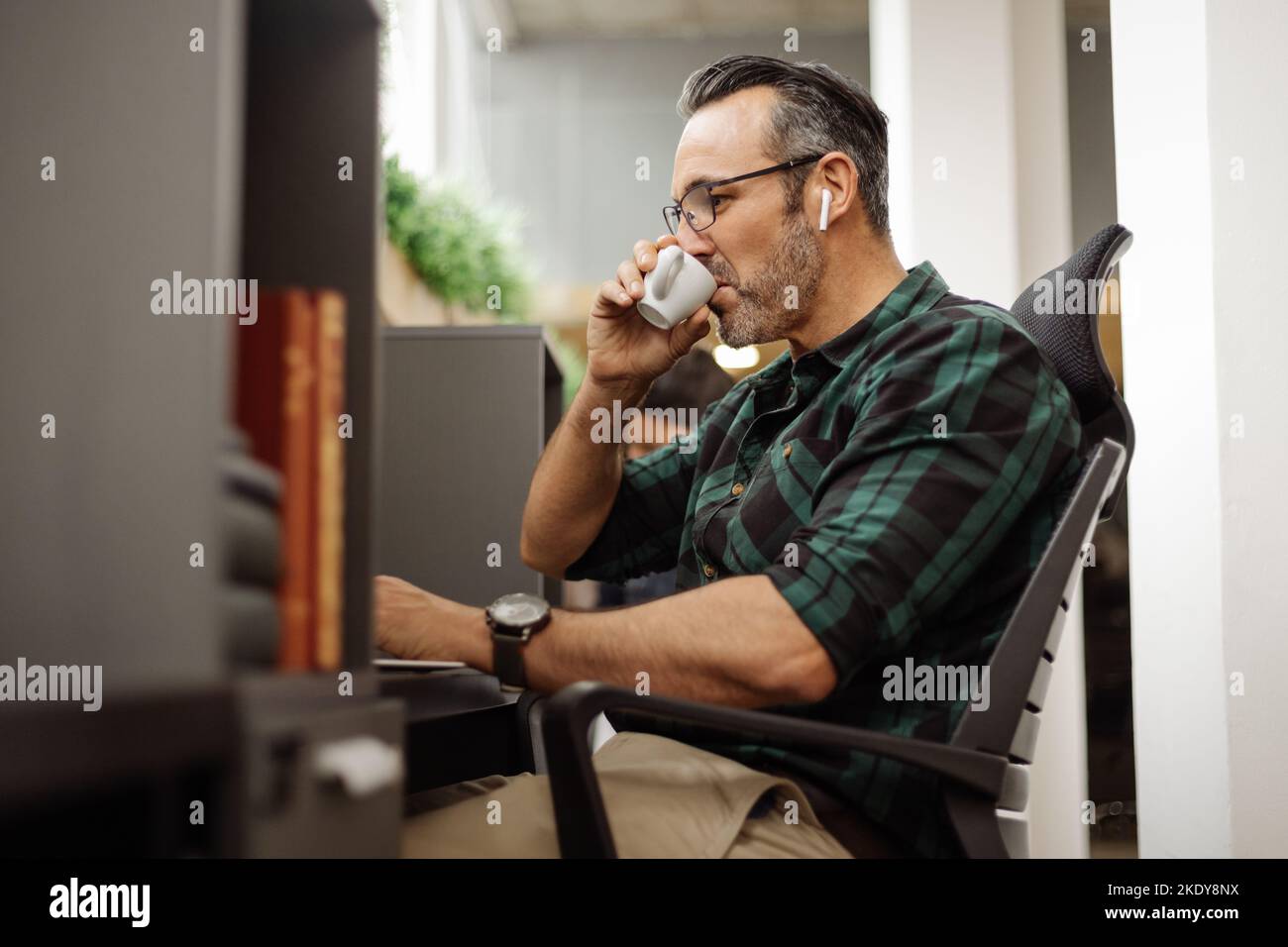 Business man sitting at private hot desk at co working office workspace