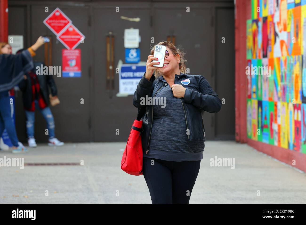 People taking selfies with their 'I Voted in the City of New York' stickers outside a polling station in Manhattan Chinatown, New York, Nov 8, 2022. Stock Photo