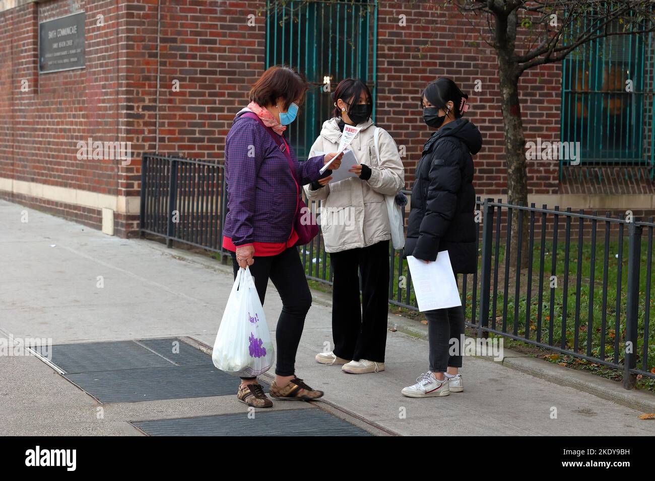 Two Asian American women with multilingual endorsement fliers electioneering outside a polling station in Manhattan Chinatown, New York, Nov 8, 2022. Stock Photo