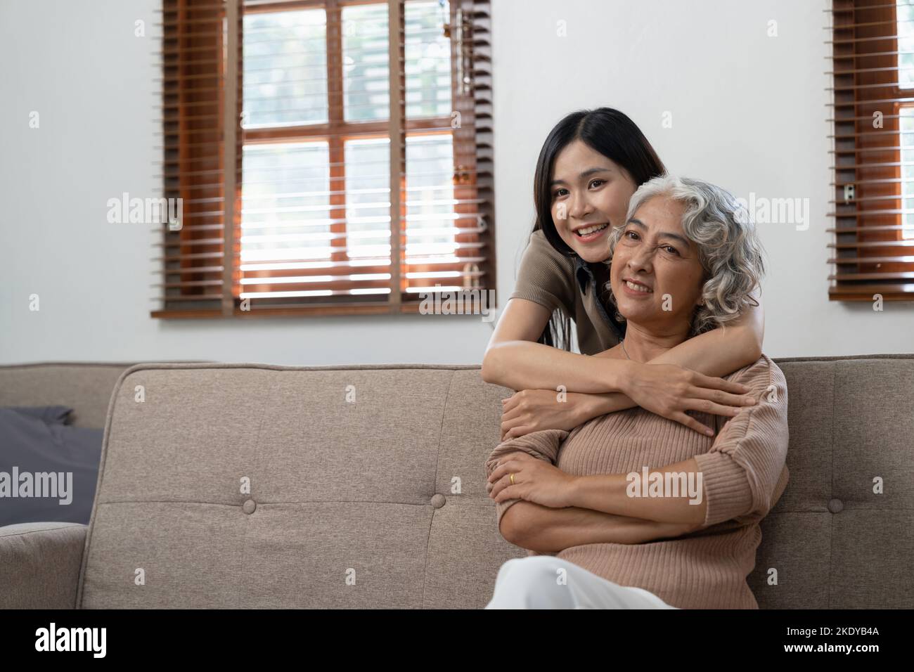 smiling grownup daughter hugging older mother. two generations concept, beautiful young woman embracing mature woman, posing for photo together. Stock Photo