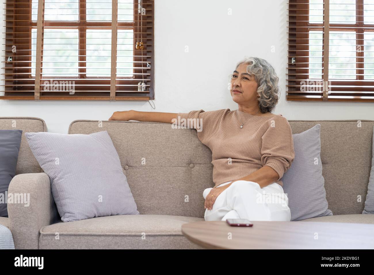Asian elderly senior female at nursing home living room feeling sad missing unhappy thoughtful in mental health care in older people. Stock Photo