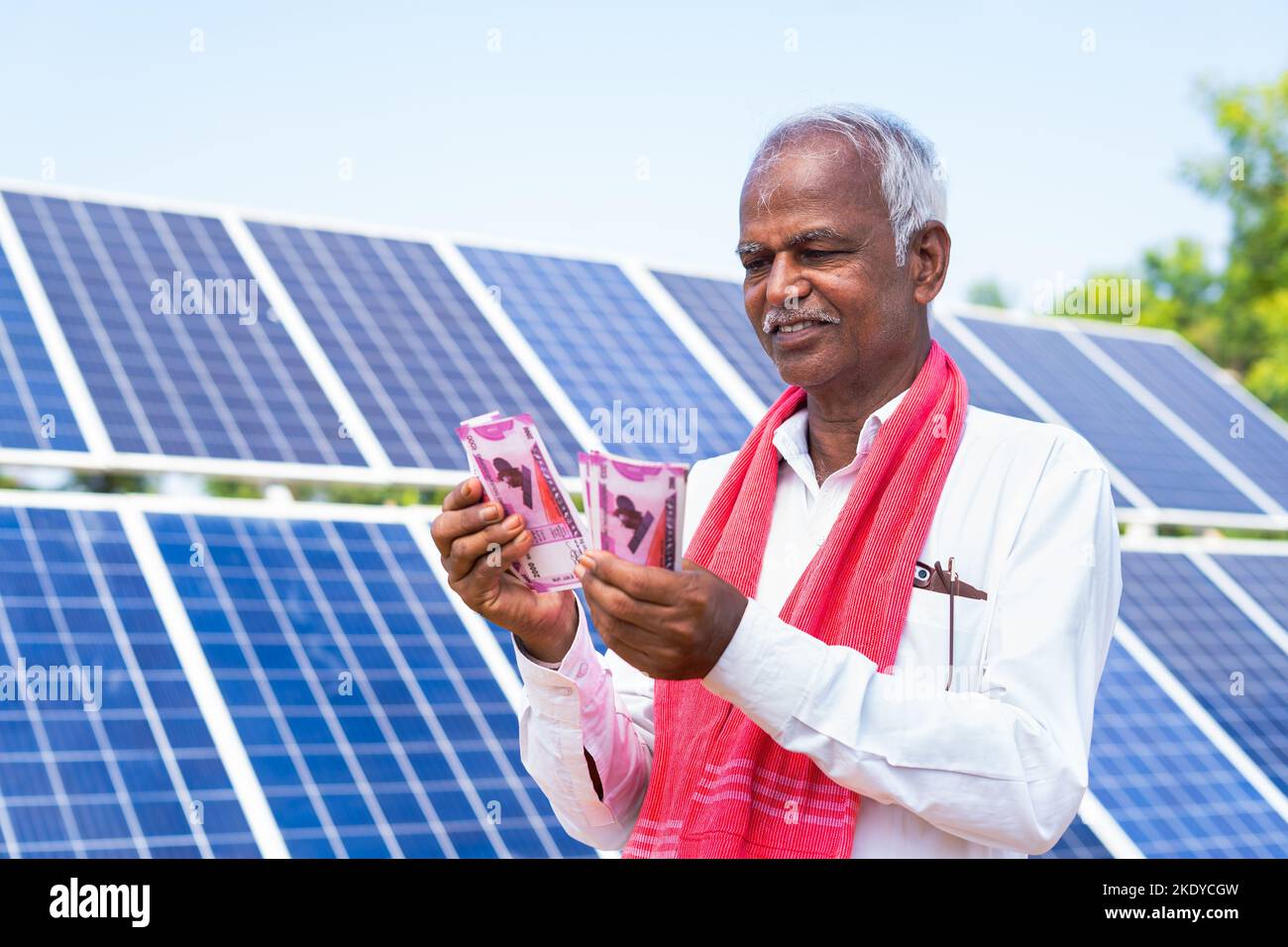 Happy farmer counting money or currency notes in front of solar panel at farmland - concept of loan approval, bank subsidy and savings or investment. Stock Photo