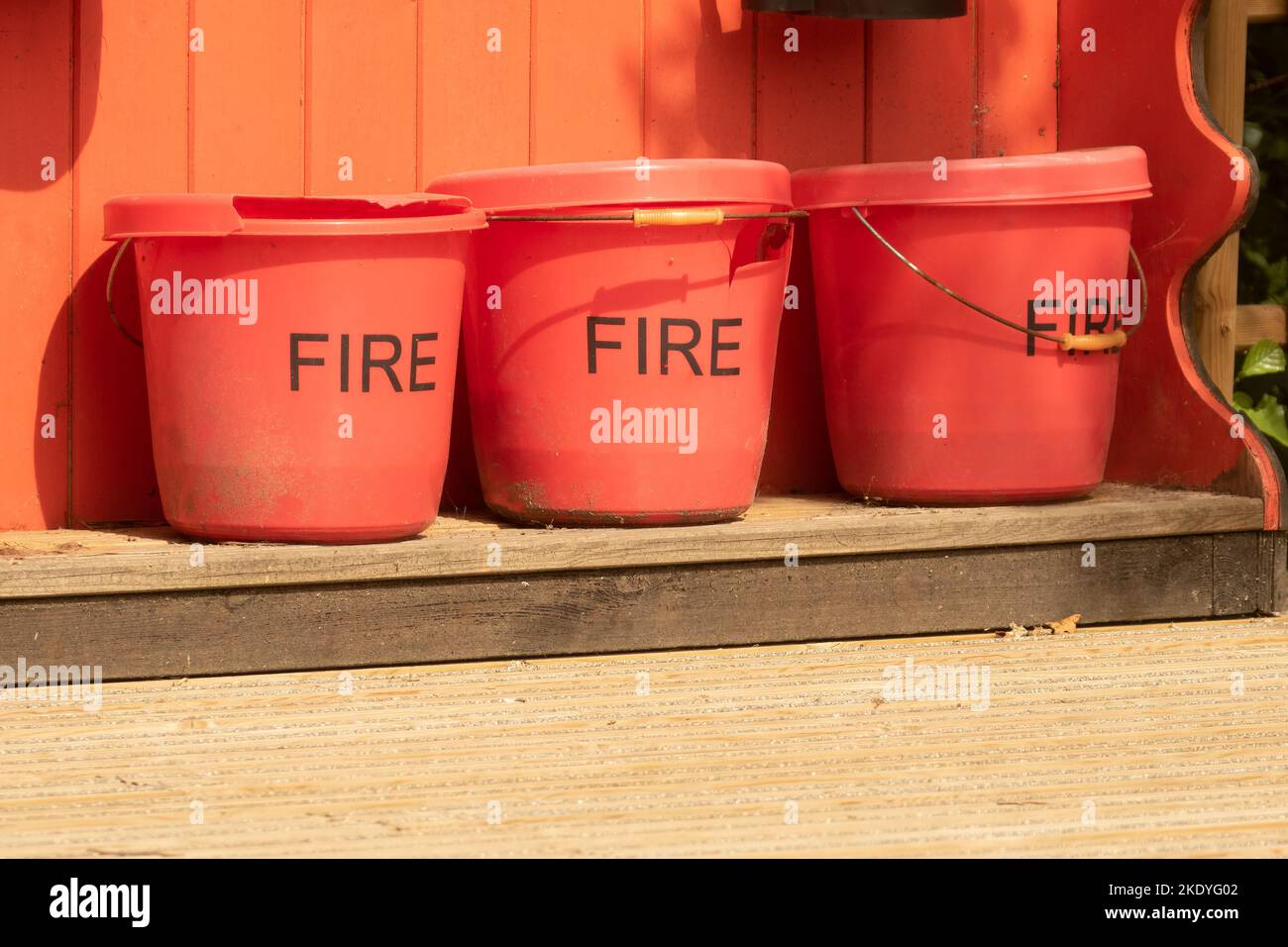 Three red fire buckets in line at the emergency station in the forest