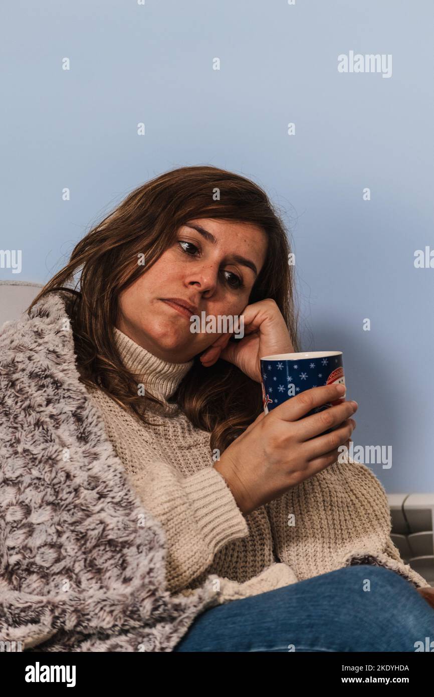 a woman sipping a hot drink while looking pensive Stock Photo - Alamy