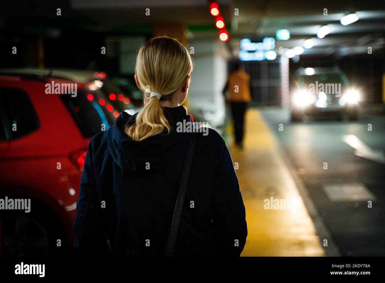 A rear view of a blonde woman standing at a parking lot Stock Photo - Alamy