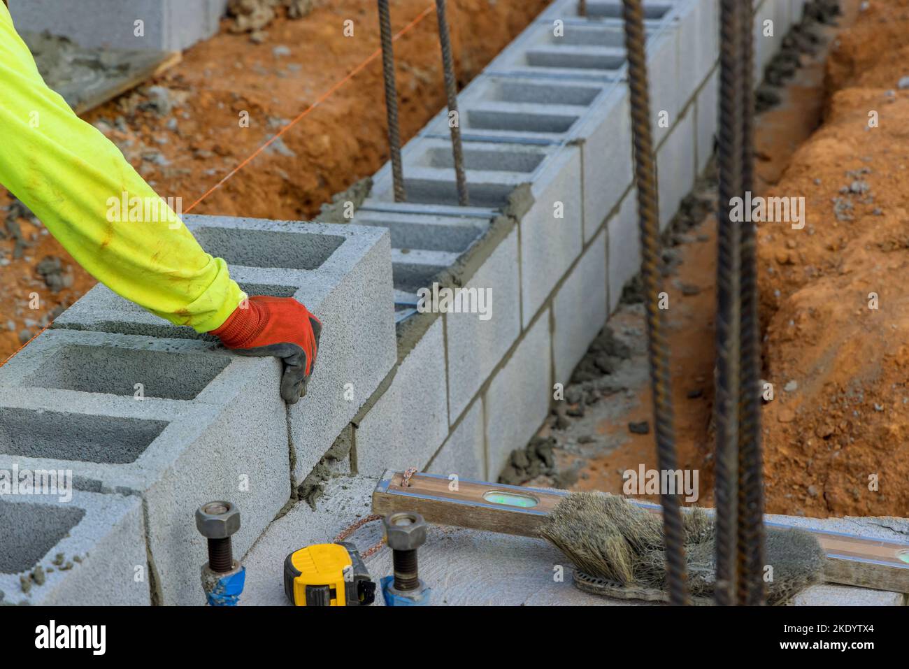 Another row of cement blocks is being laid down by bricklayer construction worker Stock Photo