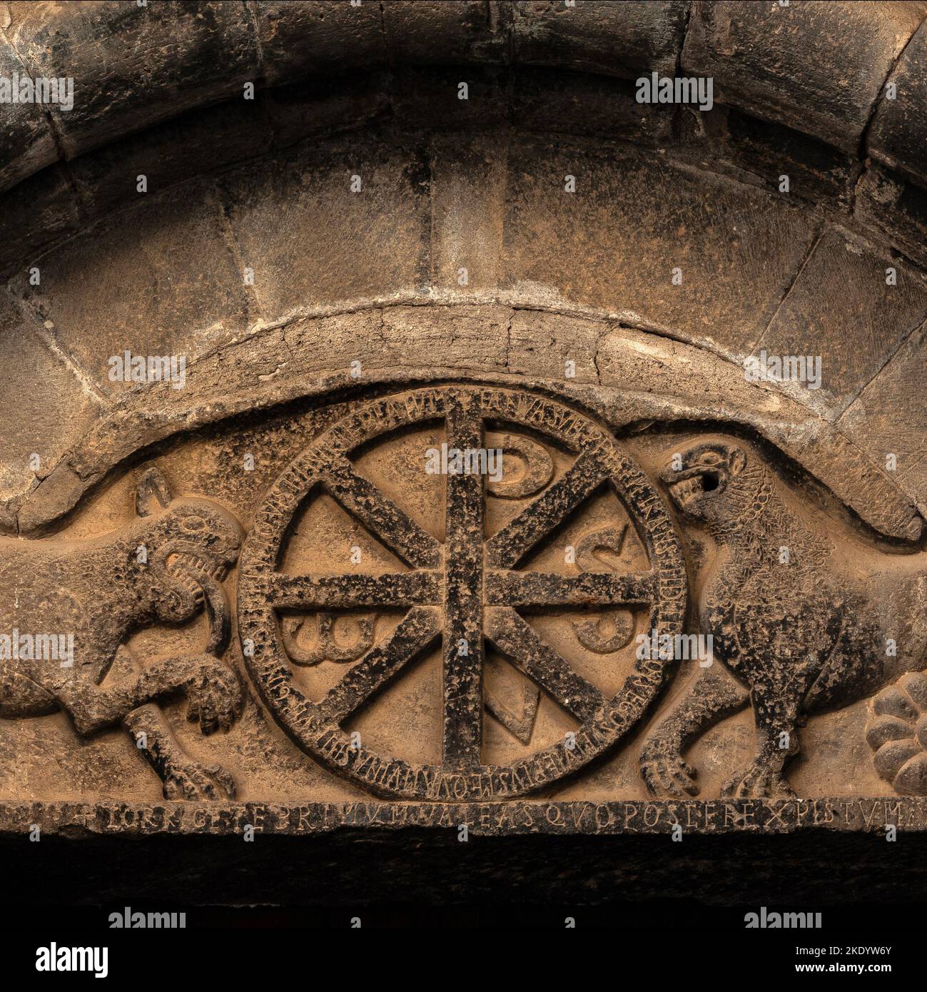 Snarling lions and Christian symbols.  Sculpted Romanesque tympanum over north portal of 11th century former Aragonese royal nunnery church of Santa Maria at Santa Cruz de la Serós in Huesca, Aragon, Spain.  It also features a Latin inscription urging the faithful to enter “this blessed temple of the Virgin”. Stock Photo