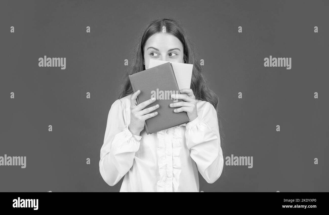 kid in white shirt ready to study do homework behind book on red