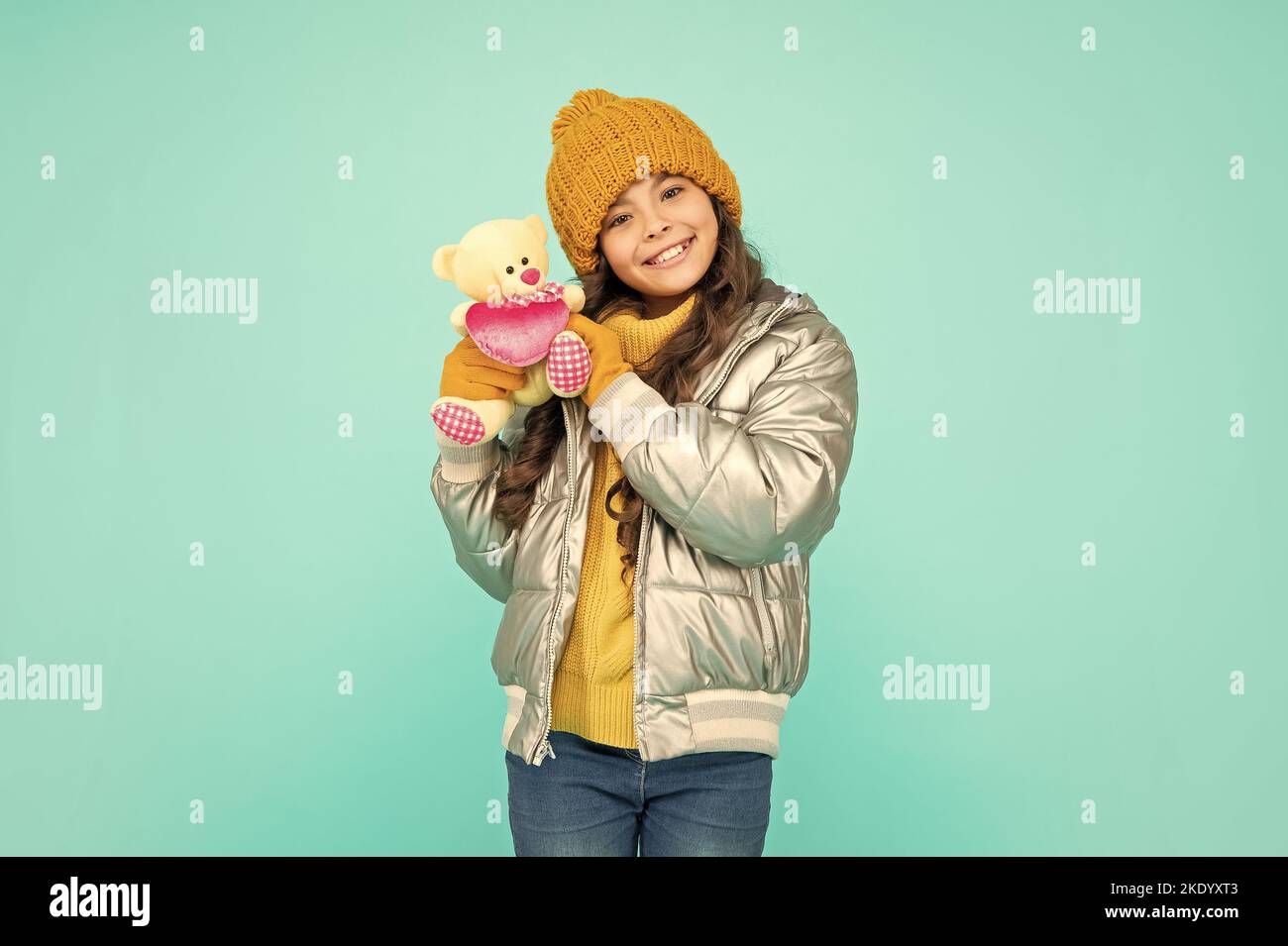 cheerful kid in hat and gloves hold toy on blue background, valentines day Stock Photo