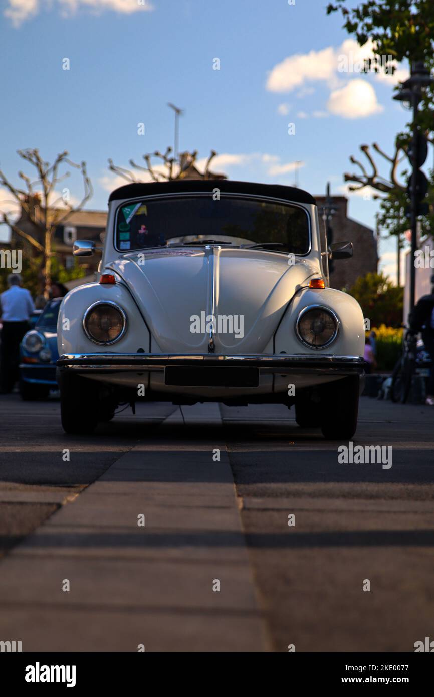 A vertical shot of a white vintage Volkswagen Beetle car on the street in Dinard, France Stock Photo