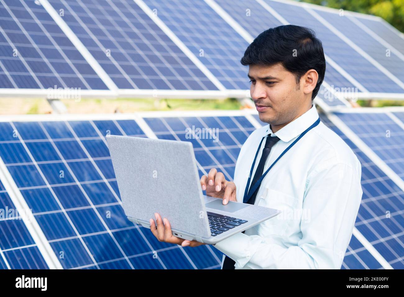 engineer or employee working on laptop in front of solar panel at farmland - concept of technology, sustainable lifestyle and professional occupation. Stock Photo