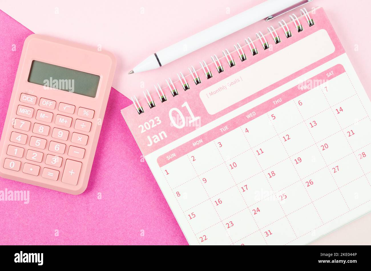 January 2023 desk calendar for 2023 year with calculator and pen on pink color background Stock