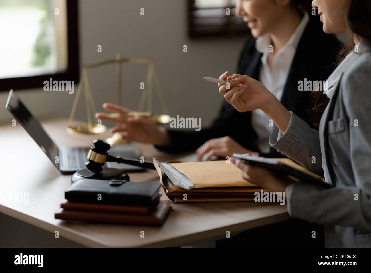 Business woman and lawyers discussing contract papers with brass scale on wooden desk in office