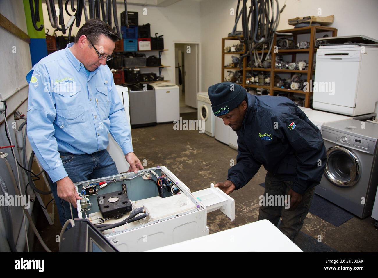 Diverse repairmen fixing a broken washing machine in the repair shop