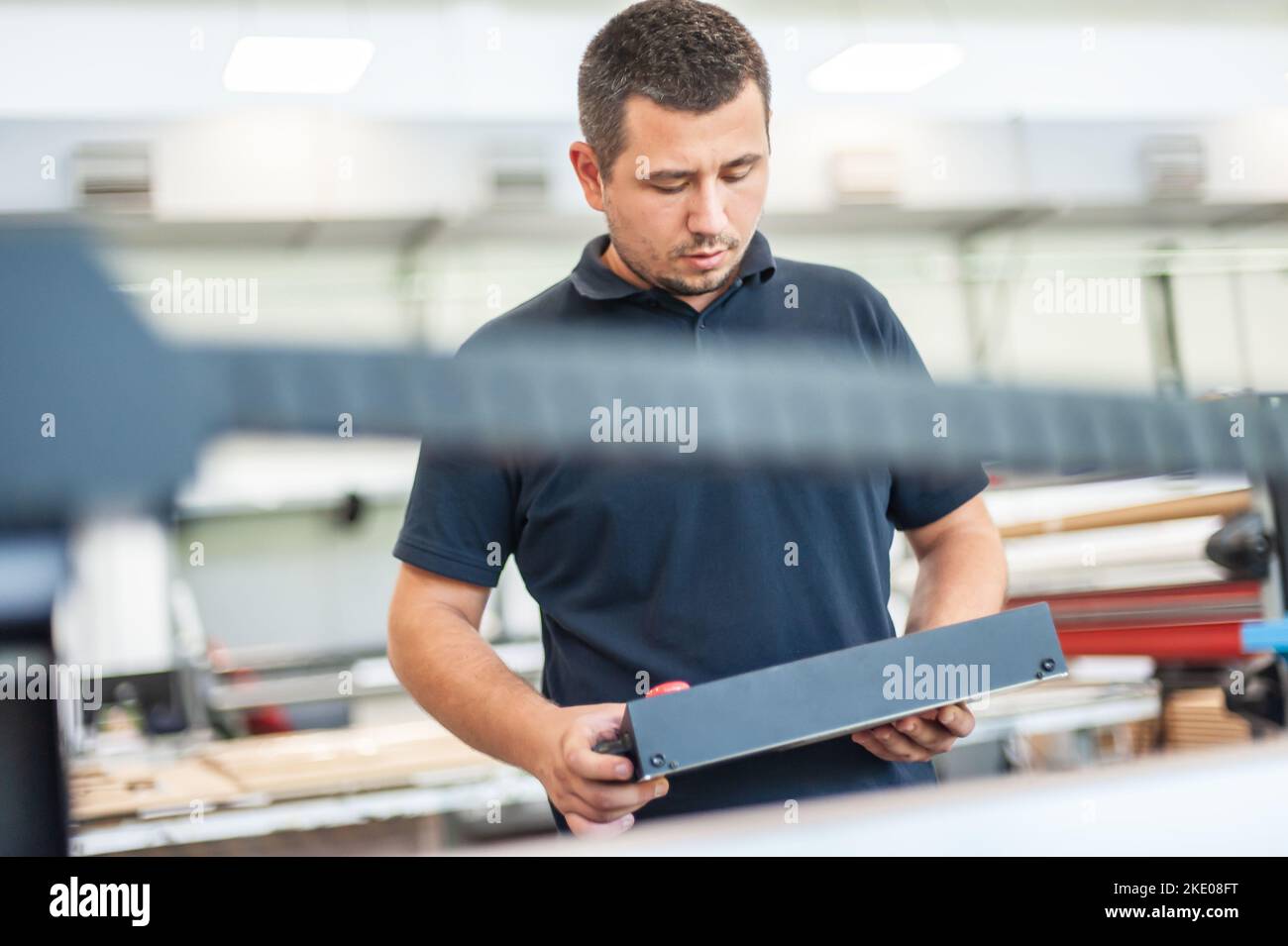 In the printing house, an experienced technician works on a UV printer. Production work. Check