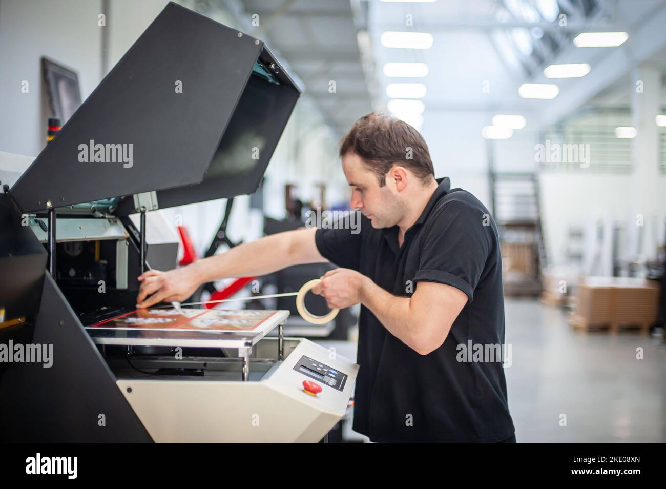 In the printing house, an experienced technician works on a UV printer. Production work. Check