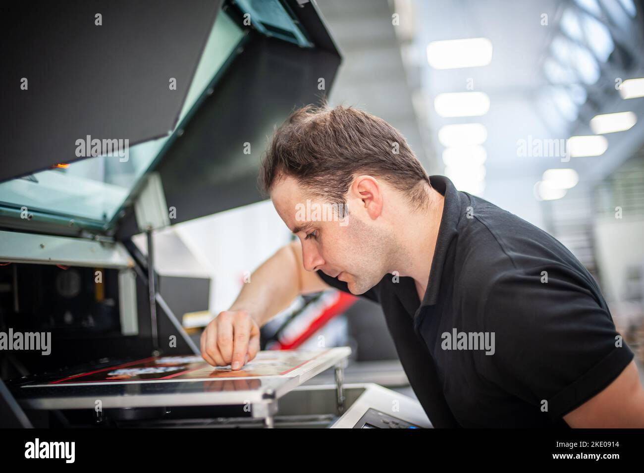 In the printing house, an experienced technician works on a UV printer