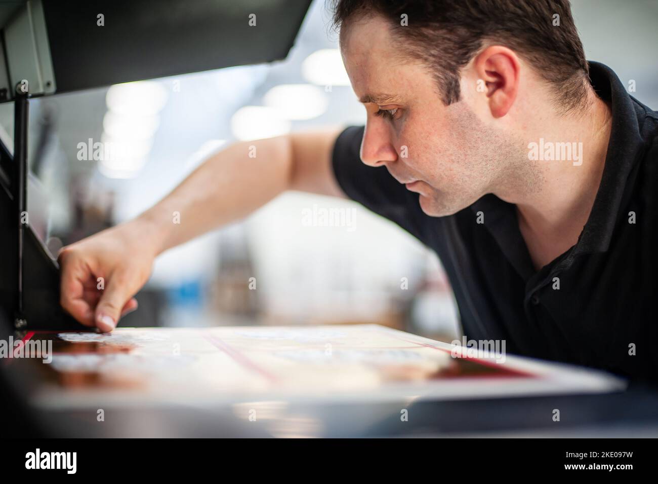 In the printing house, an experienced technician works on a UV printer. Production work. Check