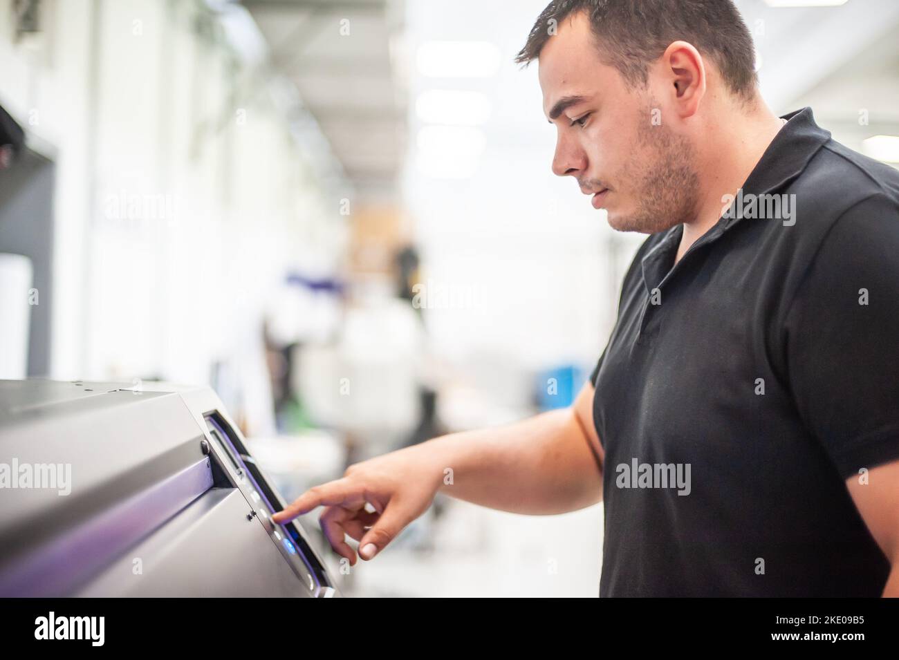 In the printing house, an experienced technician works on a UV printer. Production work. Check