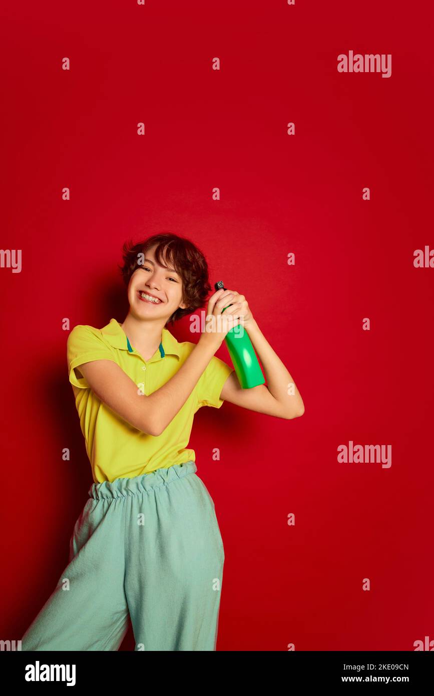 Portrait of cheerful teen girl with curly brown short hair posing with