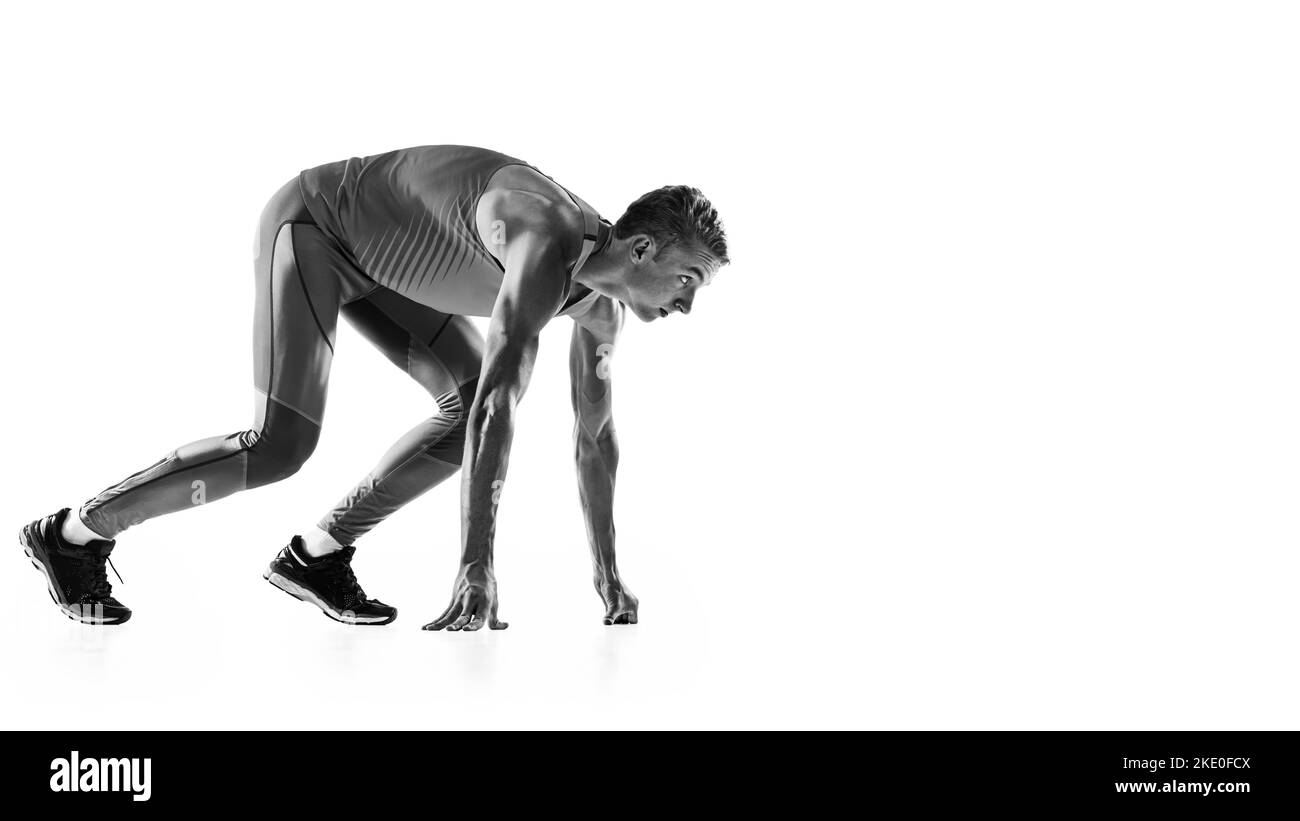 At start line. Black and white portrait of muscular male athlete, runner, jogger in motion isolated on white background. Monochrome. Sport, beauty Stock Photo