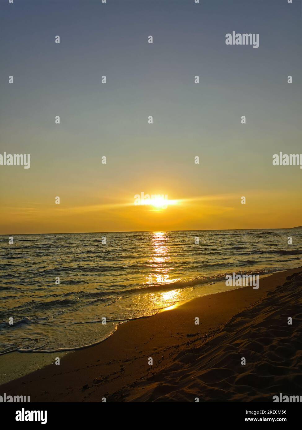 A beautiful sunset over the sea waves flowing to the sandy beach Stock ...