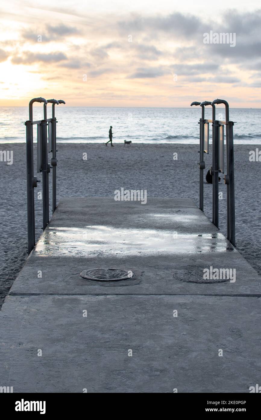 A vertical shot of outdoor showers on Camps Bay beach at sunset in Cape