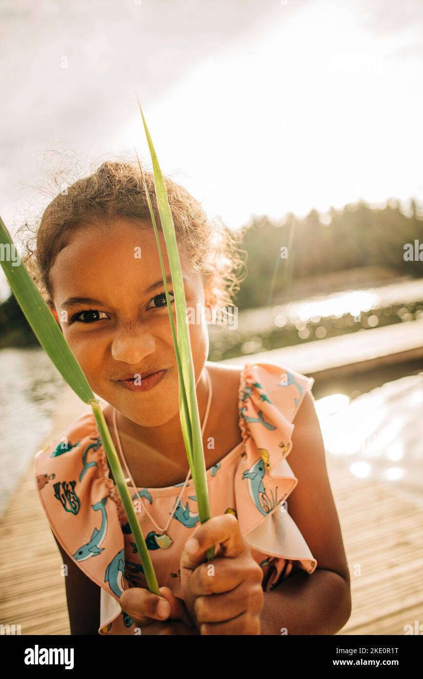 Girl making facial expression while holding blade of grass Stock Photo