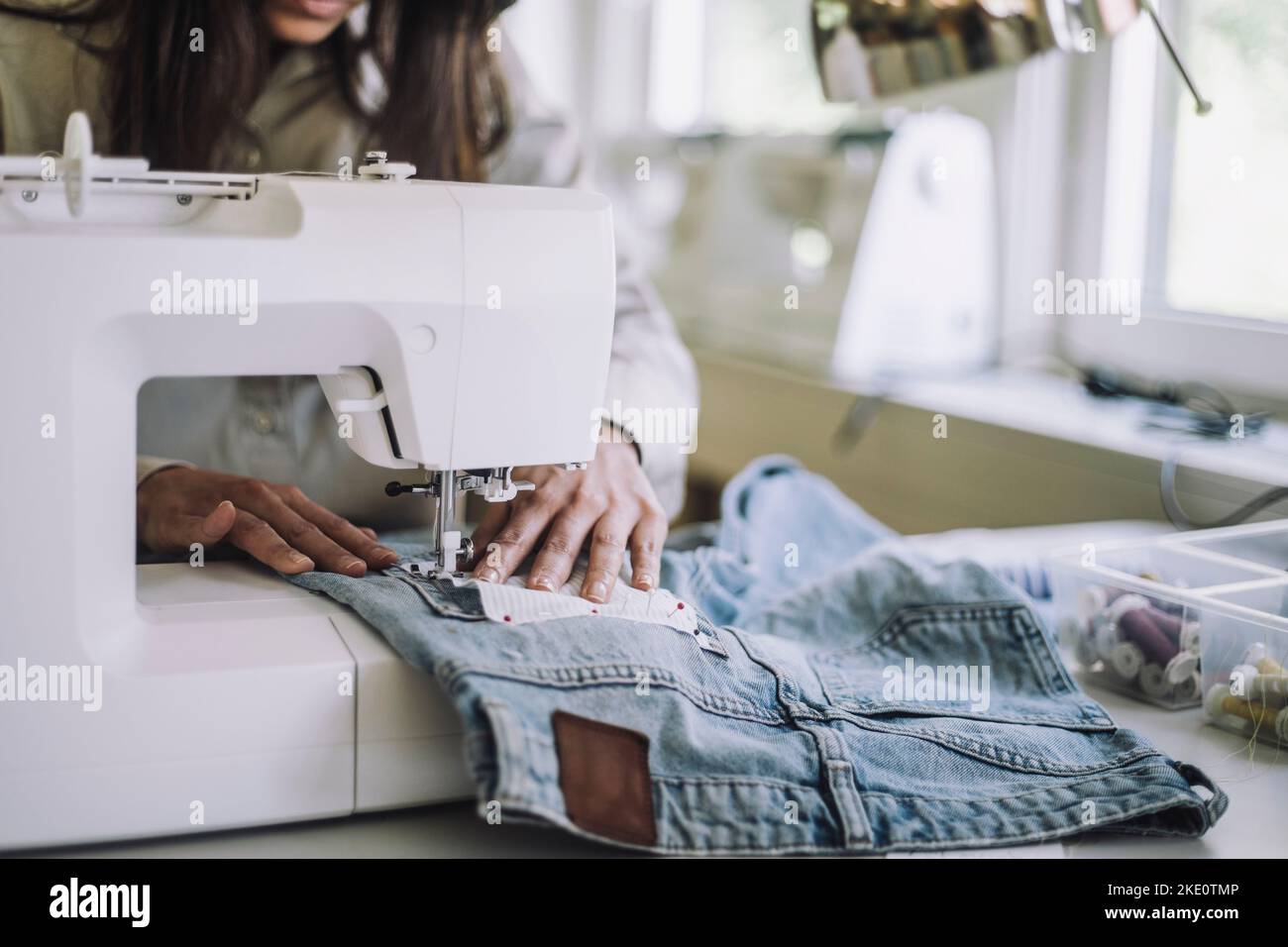 Midsection of female design professional stitching fabric through sewing machine at workshop Stock Photo