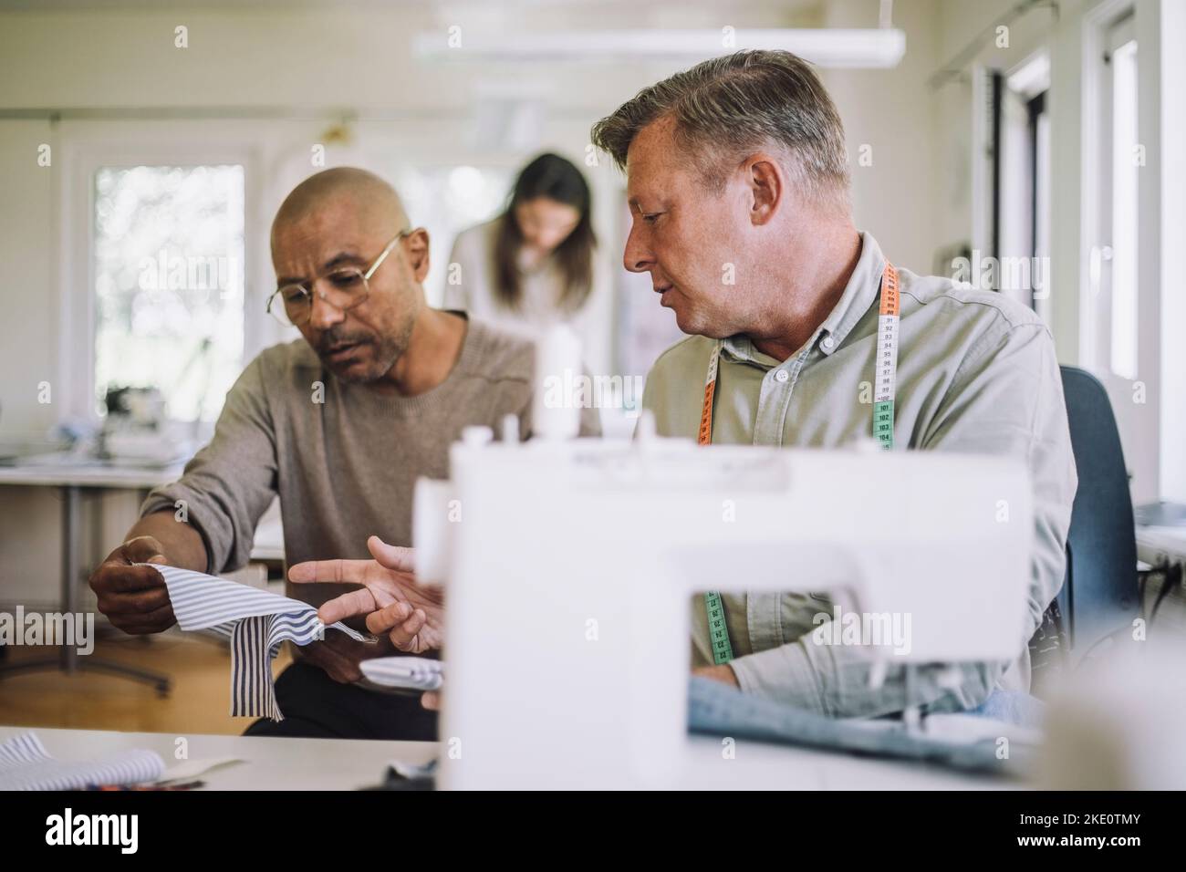 Male design professionals discussing over fabric at workshop Stock Photo