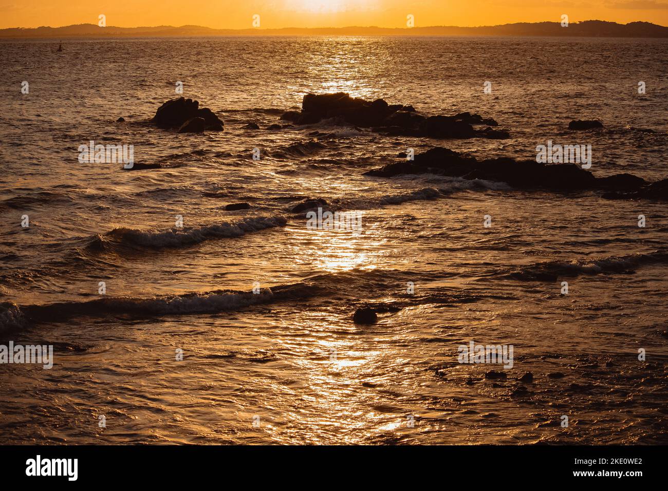 A beautiful orange sunset over the sea with splashing waves Stock Photo ...