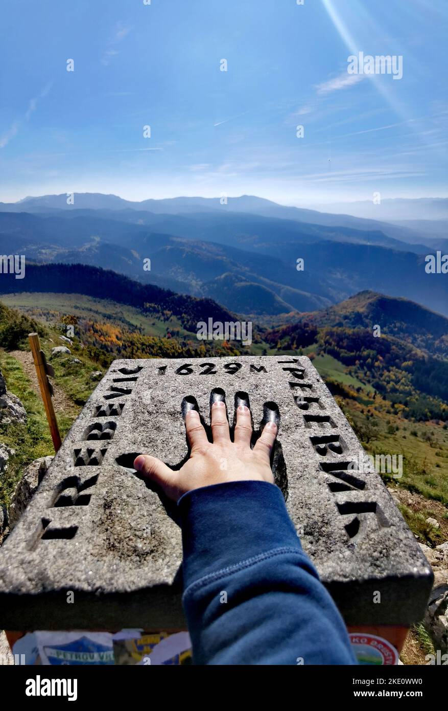 The vertical view of a hand on the landmark stone on top of mount ...