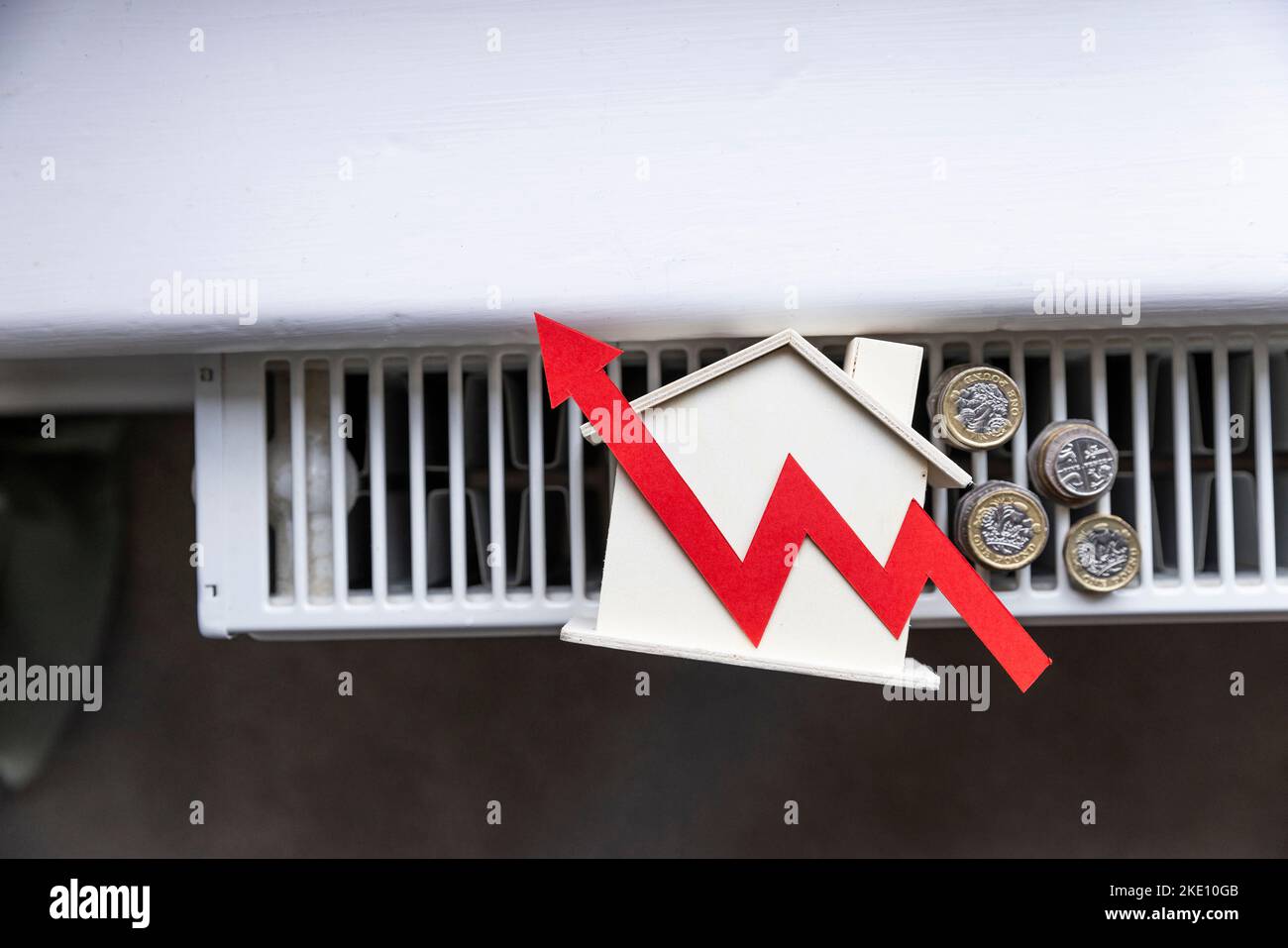 Home heating bills increase. Red up arrow with a house on a heating radiator Stock Photo