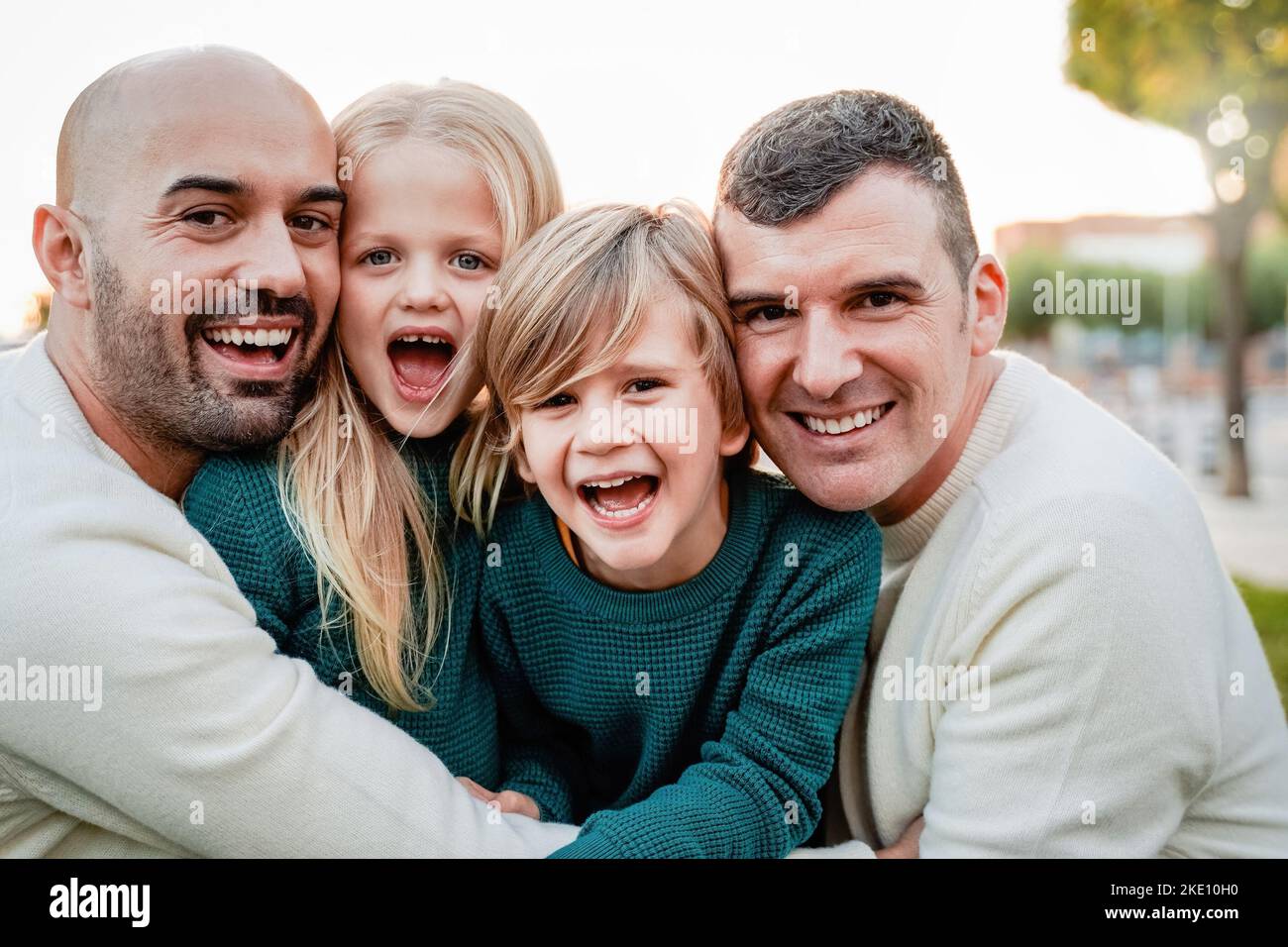 Gay male family having fun with children outdoors together in winter time - Lgbt community concept - Focus on left father face Stock Photo