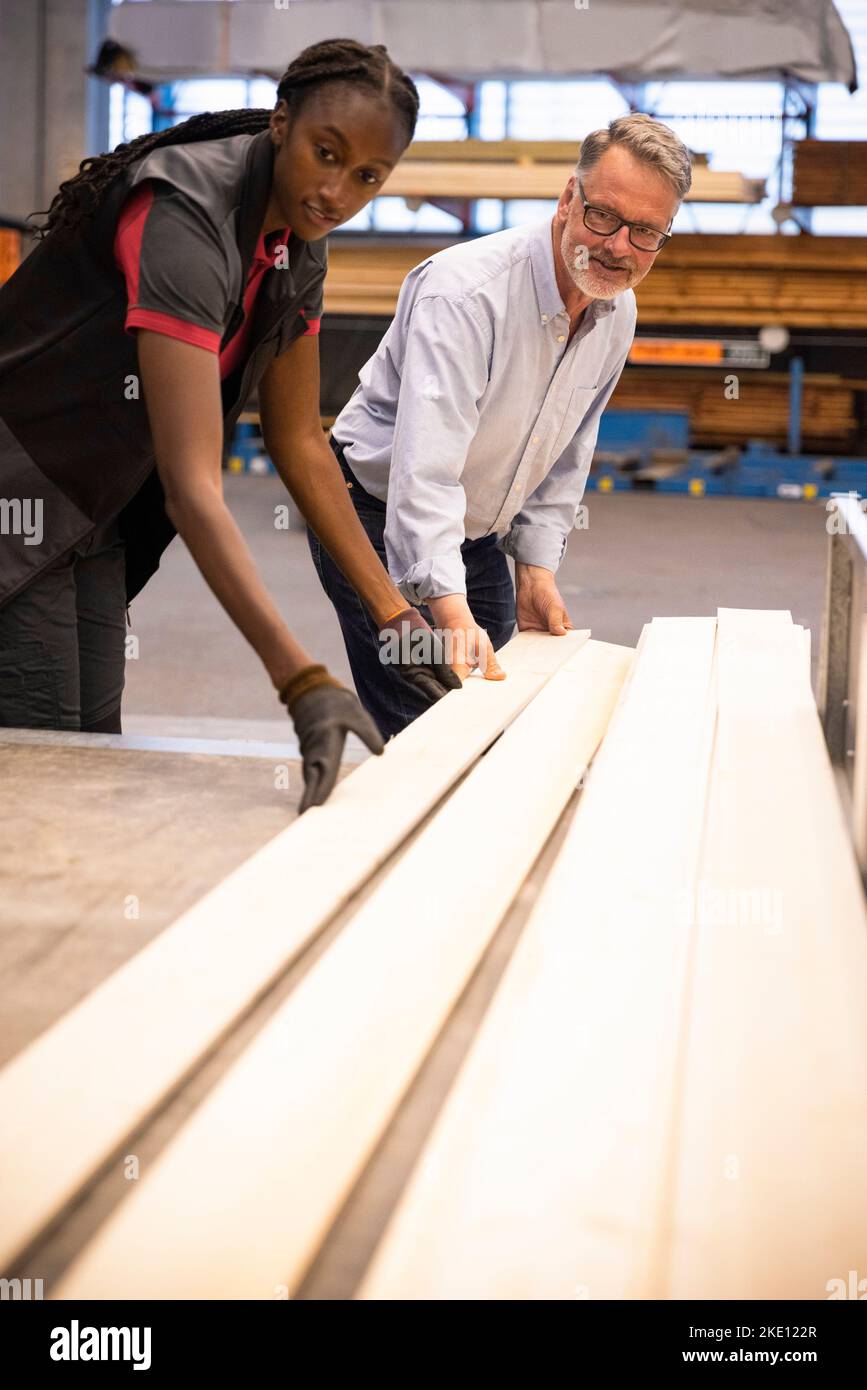Male customer and saleswoman loading planks in trailer at hardware ...