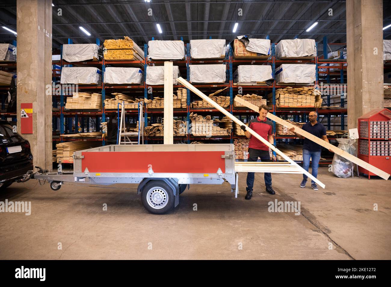 Salesman and male customer loading planks in trailer at hardware store ...