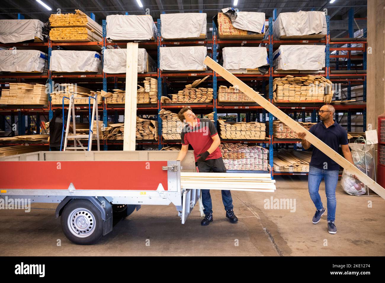 Male customer loading wooden plank in trailer at hardware store Stock
